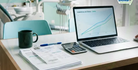 Mesa de consultório com laptop mostrando gráfico financeiro e notas fiscais organizadas